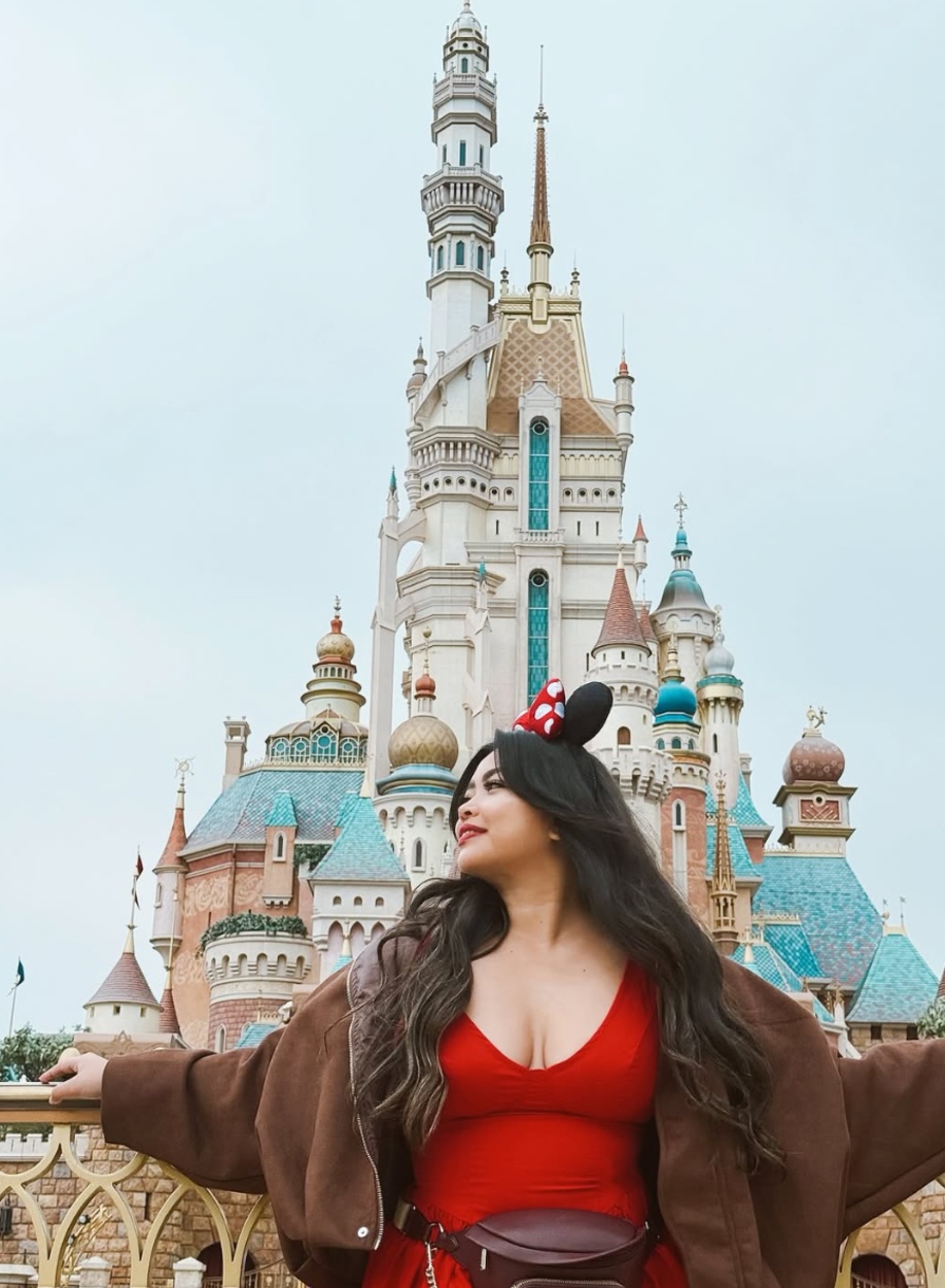Jhayde in a red dress in front of the castle at Hong Kong Disneyland